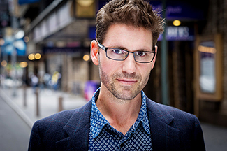 "portrait of a man with glasses, a suit coat and short brown hair set in a metropolitan scene"